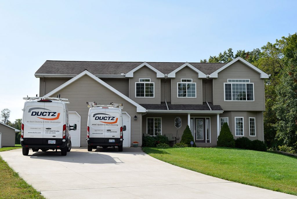 picture of the front of a house with DUCTZ vans in driveway top air duct cleaning franchise
